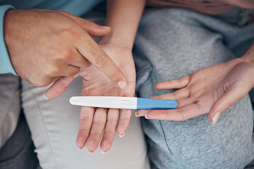 Hands, couple and closeup of pregnancy test, results and waiting for news together in home. Top view, kit and pregnant woman and man family planning for future maternity, ivf fertility and support
