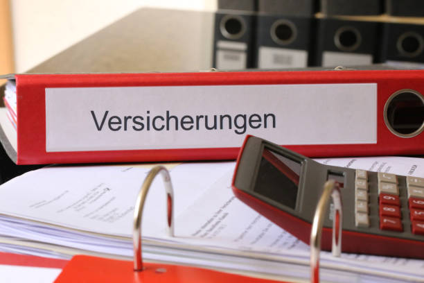 istock Symbol image: Folder (labelled Versicherungen, Insurance in German) with insurance policies and calculator on a desk (German) 1772129096
