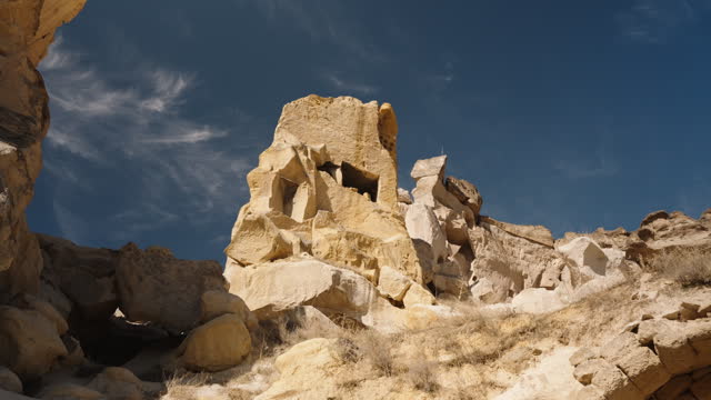View of ancient dwellings carved into massive rocks against the backdrop of the blue sky.
