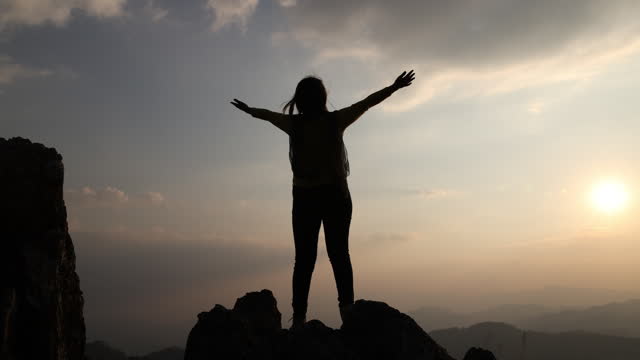 Silhouette of a young woman standing with arms spread out. Homeopathy Good health. Confess your sins and hope to praise God.
