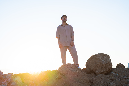 Young influencer stands and poses on a hill.