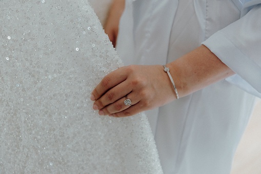 A woman's hand is touching the fabric of the wedding dress