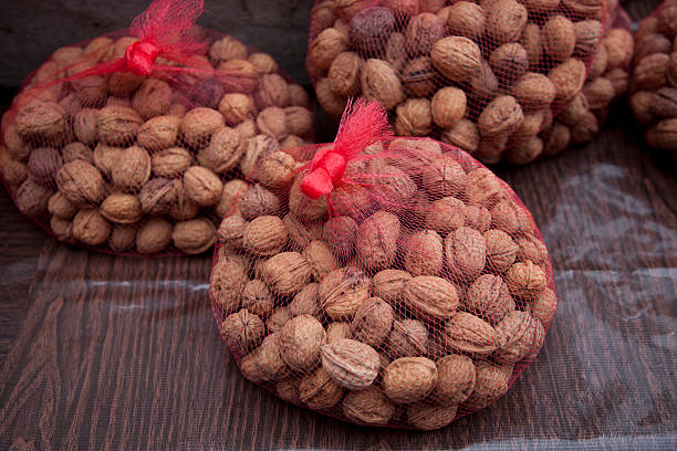 Whole walnuts in red net bag at farmers market stock photo