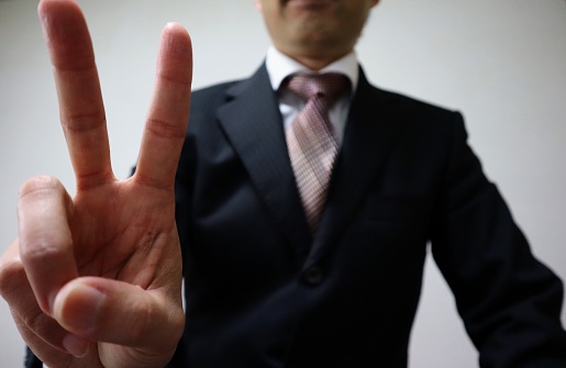 Close-up photo of businessman doing peace sign