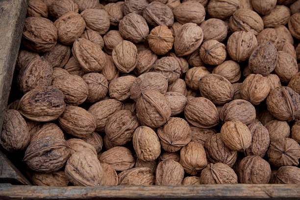 whole walnuts in wooden crate at farmers market stock photo