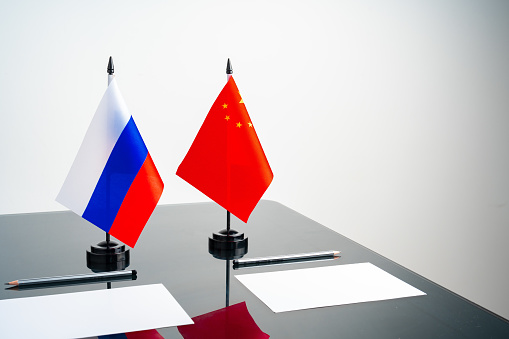 Russian and Chinese flags on negotiation table close up