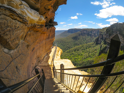 wooden stairs at hiking trail along the cliff with beautiful mountain view of Wentworth Falls, deep in the bushland, in the Blue Mountains National Park.