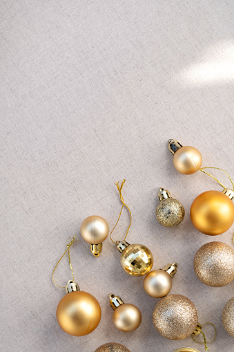 Minimalist aesthetic winter holiday backdrop, business branding template. Golden decoration balls on neutral beige linen background with natural sun light shadows, copy space.
