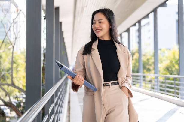 istock A beautiful Asian businesswoman is holding a document binder while walking on a skywalk. 1772246765