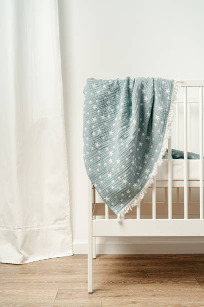 istock Soft blue muslin blanket hanging on a baby's bed 1772247358