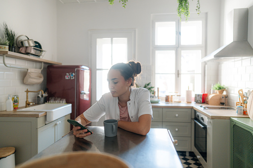 Photo of a female healthcare professional, still in her medical scrubs, checking her social media accounts while on a coffee break