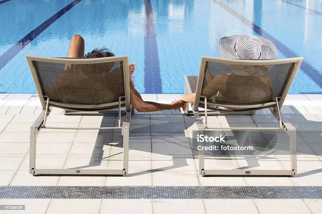Couple relaxant dans les chaises longues au bord de la piscine - Photo de Admirer le paysage libre de droits
