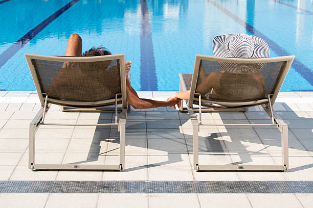 istock Couple relaxing in deck chairs by the swimming pool 177226120