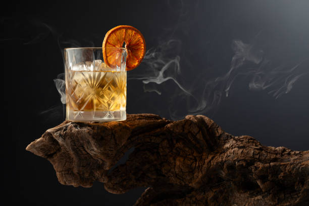 Smoked old fashioned cocktail with ice and dried orange slice. Smoked old fashioned rum cocktail with ice and dried orange slice on a old wooden snag. Copy space. amber black photography stock pictures, royalty-free photos & images