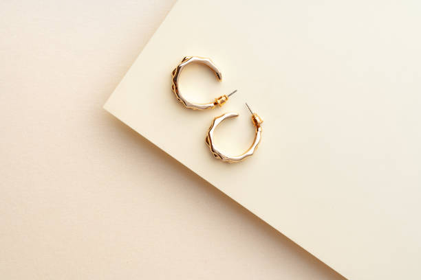 istock Golden earrings on paper background studio shot 1772263177