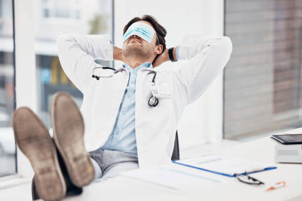 Man, doctor and sleeping with face mask on break or relax for done, completion or finished at hospital office. Tired male person or medical surgeon chilling for rest or asleep on work desk at clinic hombre, médico y durmiendo con mascarilla en el descanso o relájese para hacer, completar o terminar en la oficina del hospital. persona masculina cansada o cirujano médico que se relaja para descansar o dormir en el escritorio de trabajo en la clínica
