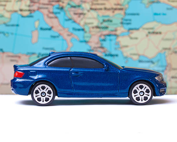 Blue toy car on vacation Blue toy car on white surface with map in the background toy car stock pictures, royalty-free photos & images