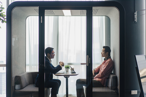Business - Meeting in a sound proof capsule for privacy between two Asian executives
