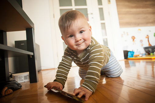 Portrait of cute happy smiling baby boy crawls on the home floor and looking at camera. Joy and happiness concept. Love and family emotion