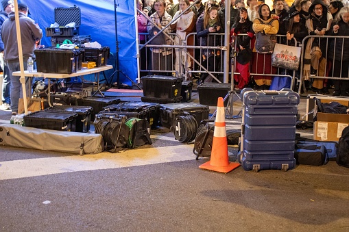 nyc, United States – November 01, 2023: Numerous suitcases resting in front of a security barrier, with a group of travelers surrounding the area