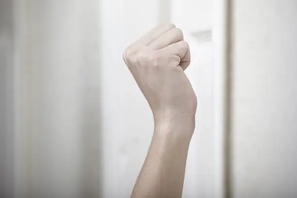 Human hand knocking at the wooden door