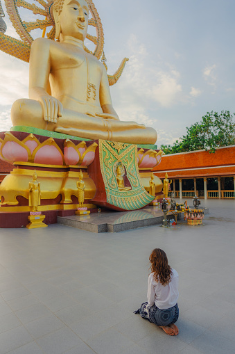 Woman in prayer pose sitting near  Big Buddha Temple in Koh Samui, Thailand