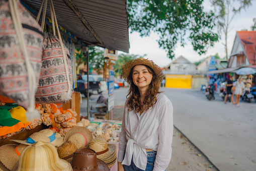 Woman buying straw w hat in souvenir shop in Thailand