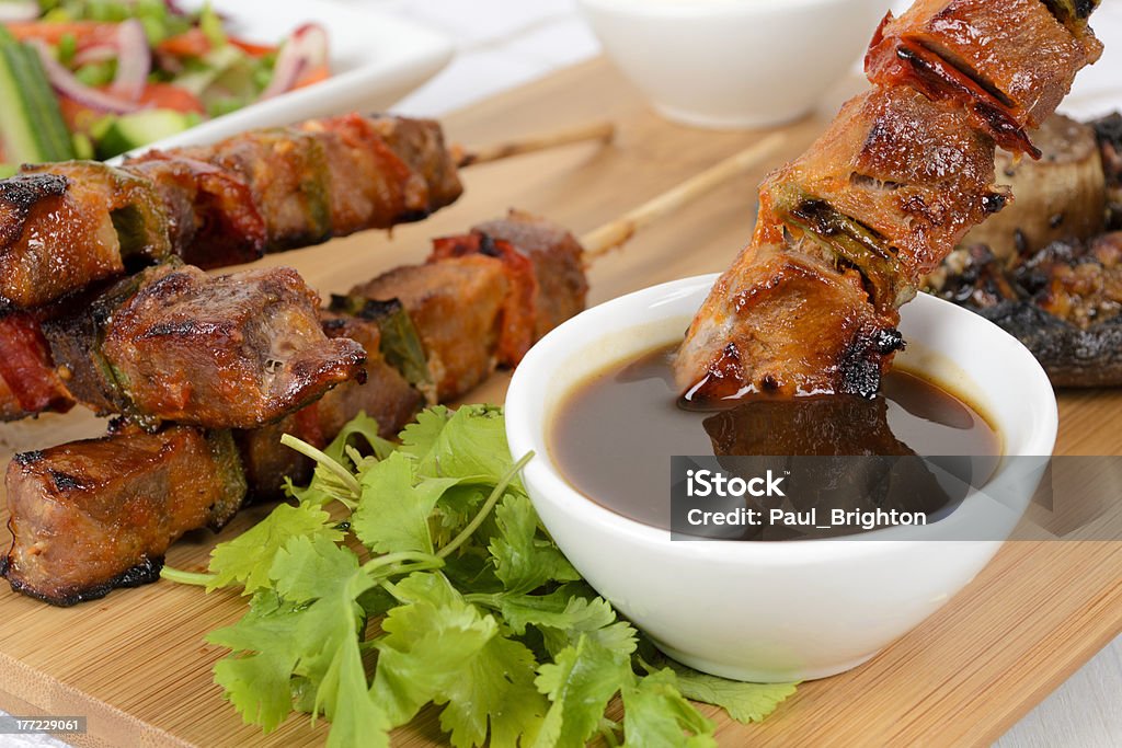 BBQ Glazed Pork Kebabs "Grilled pork kebabs on wooden skewers with peppers. Served with salad, grilled mushroom, BBQ sauce and and sour cream dip." Abdomen Stock Photo