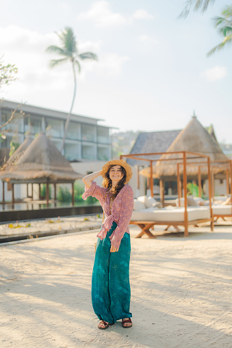 Woman with straw hat walking on the beach during tropical vacation