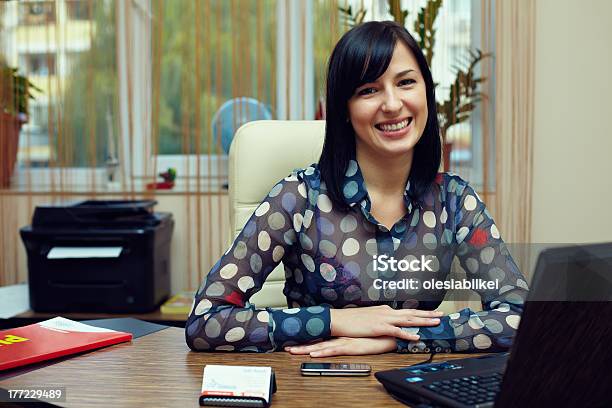 Attraktive Freundliche Frau Sitzt Im Büro Am Arbeitsplatz Stockfoto und mehr Bilder von Drucker - Computerteil