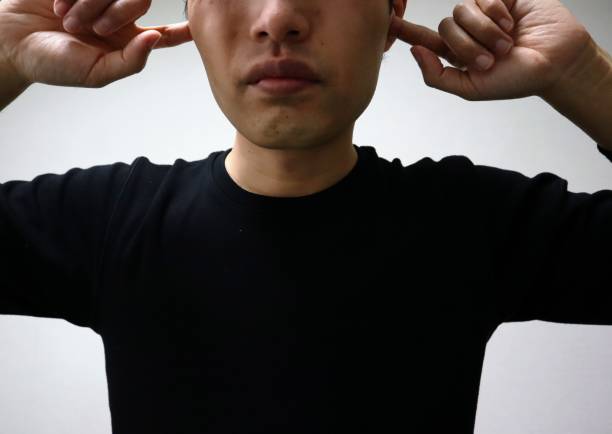 Close-up of a Japanese man covering his ears