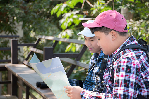 Asian boys are at the local national park to do birdwatching and to learn plants, insects, trees, landscapes, river, underwaterplants and animals which lived in the local national park.