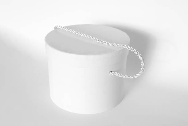 istock Single blank textured round box, gift with rope and its lid lean on it isolated on light white background. Mockup With shadow 1772316065