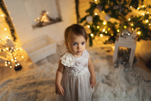 Young girl in beautiful dress at decorated room celebrate Christmas and New Year.
