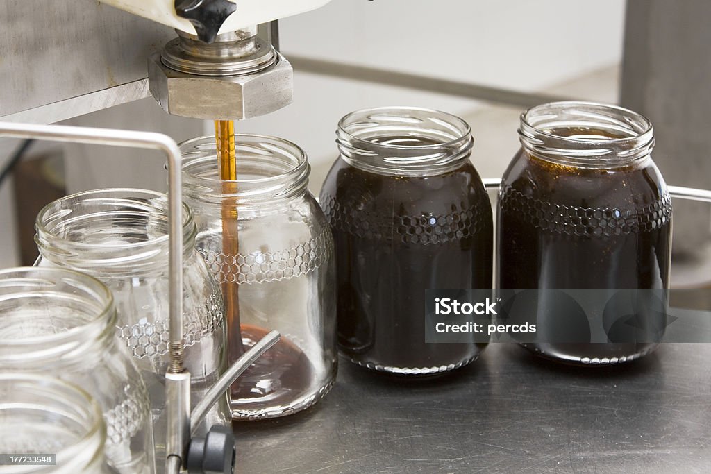 Pouring honey into storage jars Pouring organic honey into storage glass jars. Jar Stock Photo