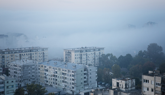 foggy autumn morning at residential district, fog enters into city