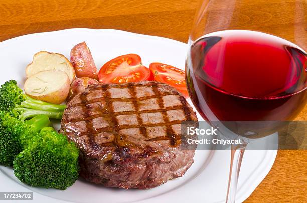 Bistecs De Carne De Res Asado A La Parrilla Y Una Copa De Vino Tinto Foto de stock y más banco de imágenes de Alimentos cocinados