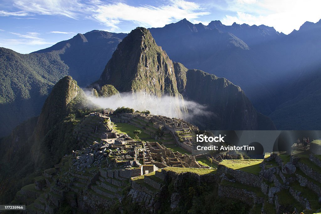 Machu Picchu at sunrise Machu Picchu at sunrise with a cloud resting on the ruins Machu Picchu Stock Photo