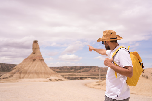 Man pointing to a rock formation in a national reserve during trekking along an arid and sandy path