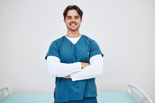 Portrait, doctor and arms crossed for smile in space for health, treatment or wellness. Happy man, physiotherapist and scrubs for career in medicine by emergency care, cardiology or rehabilitation