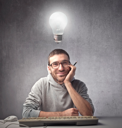 Smiling young man in front of a computer keyboard with light bulb over his head