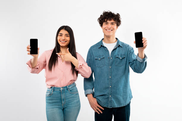 istock Cheerful Young Couple Showing Cellphones Empty Screens On White Background 1772369966