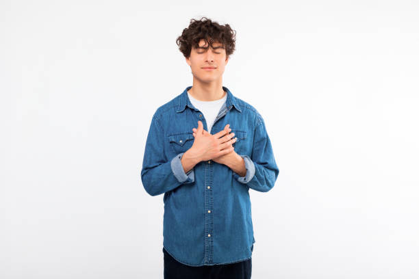 istock Peaceful guy pressing hands to chest making wish, white background 1772370020