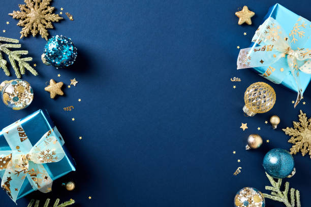istock Christmas banner, greeting card template. Flat lay composition with glitter gift boxes, golden balls, decorations, fir branches on dark blue background. Top view. 1772372850