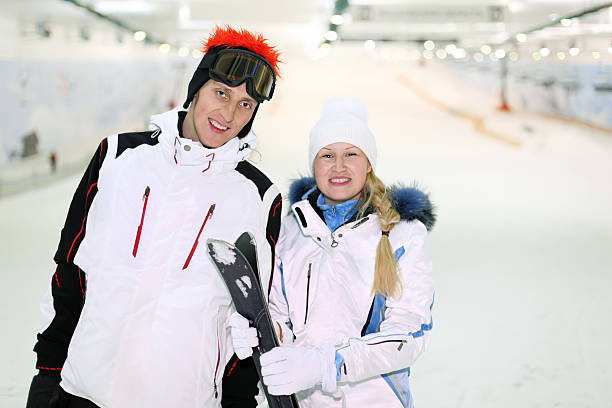 Husband and wife stand with skis in indoor ski stock photo