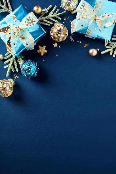 istock Christmas vertical flat lay composition with luxury gift boxes, golden balls, decorations on dark blue table. 1772377872