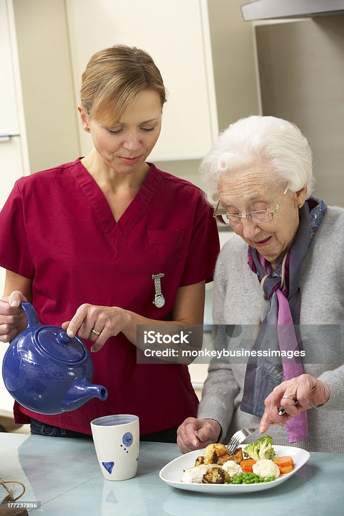 Senior woman with carer eating meal at home Senior woman with carer eating meal at home and having a cup of tea Assistance Stock Photo