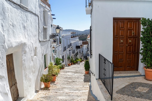 Narrow street of an Andalusian village with its white houses, pots and flowers. Frigiliana Malaga. Spain.