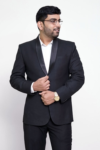 A portrait of a young Indian male wearing a suit with a white background