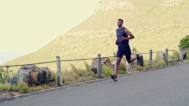 Man, running and mountains for workout, exercise and speed training, outdoor challenge or energy on road. Professional runner, athlete or young sports person with cardio, fitness and body health